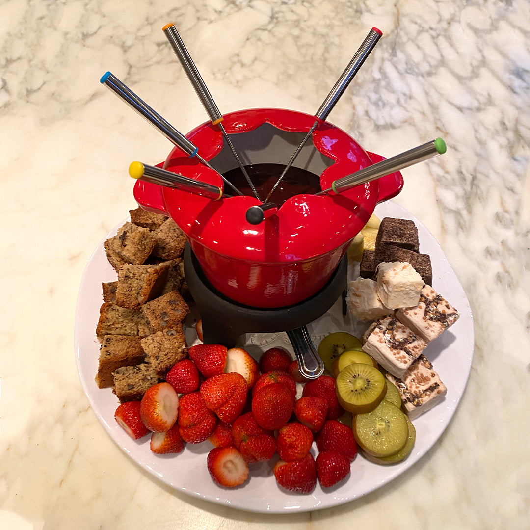 A pot of rich melted chocolate fondue surrounded by fresh strawberries, marshmallows, and dipping treats — romantic date night recipe from ekuBOX