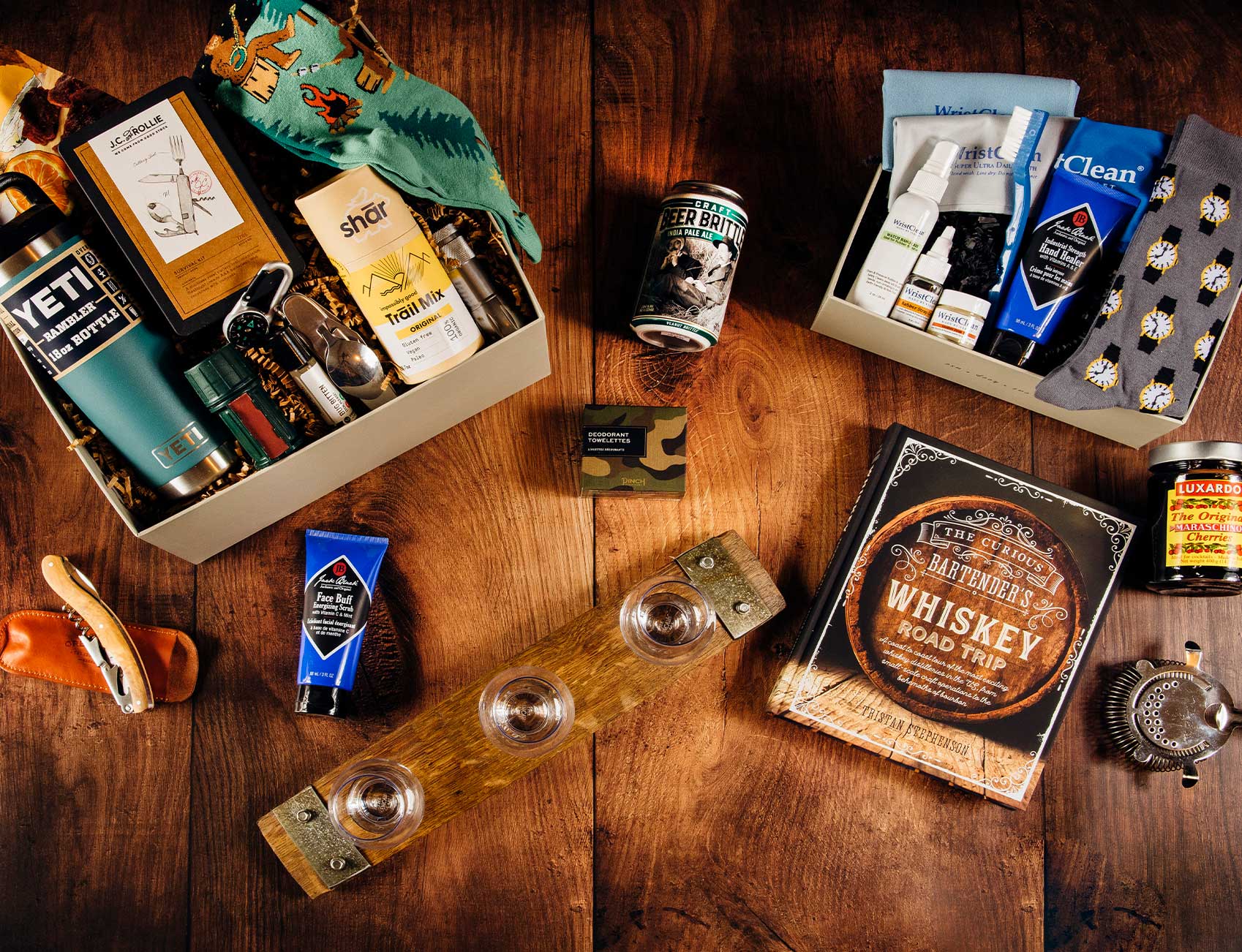 Two men’s Father’s Day gift boxes displayed on a wooden table, featuring thoughtfully curated gifts for Dad.