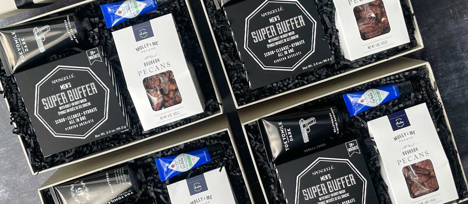 Client gift boxes arranged together, featuring candied nuts, lip balm, hand cream, and curated grooming essentials for professional gifting