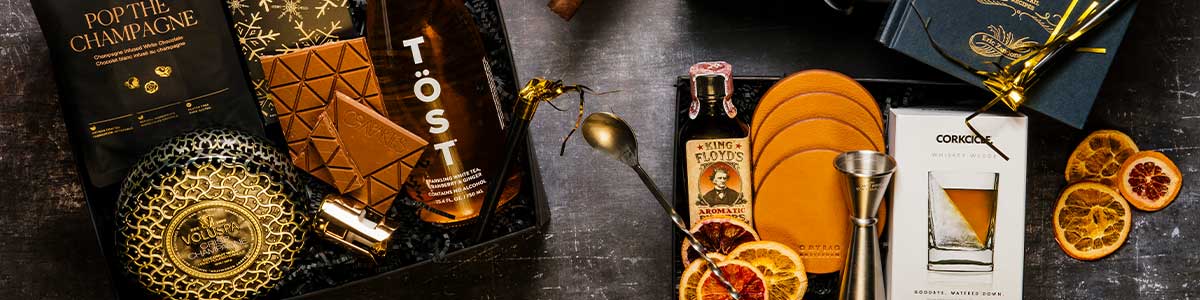 Luxury corporate gift boxes arranged on a dark background, featuring sparkling non-alcoholic champagne, champagne chocolates, and elegantly curated gifts for client and employee gifting.