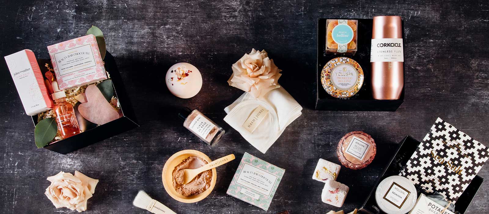 Curated luxury gift boxes for her in soft pink tones, elegantly arranged against a dark background, featuring thoughtfully packaged gifts for birthdays, celebrations, and special occasions.