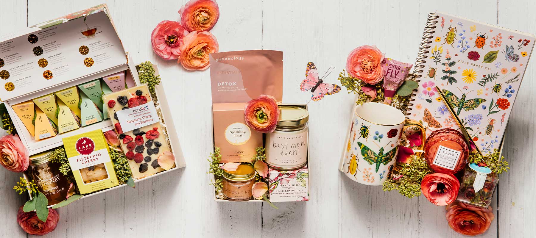 Mother’s Day luxury gift boxes featuring a butterfly mug and notebook, gourmet tea, candles, cookies, and fresh flowers, beautifully arranged for elegant gifting.