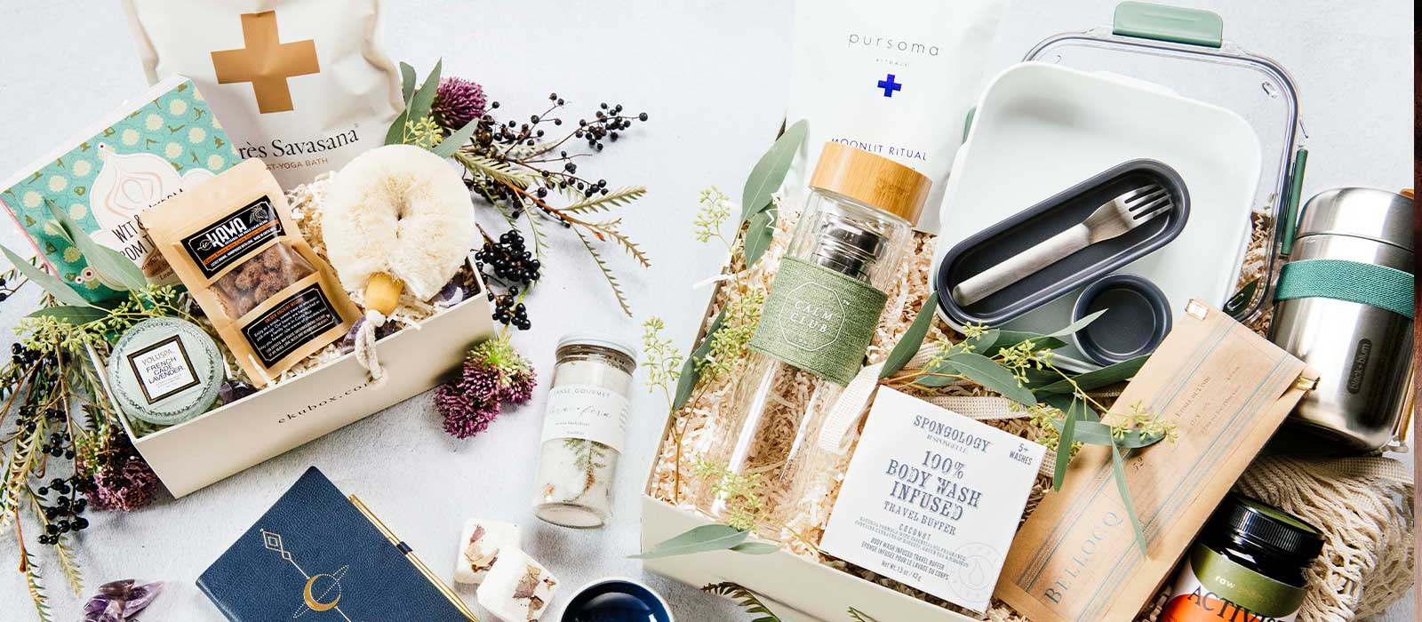 Two luxury spa gift boxes featuring wellness and self-care products, styled on a light background with wildflowers.