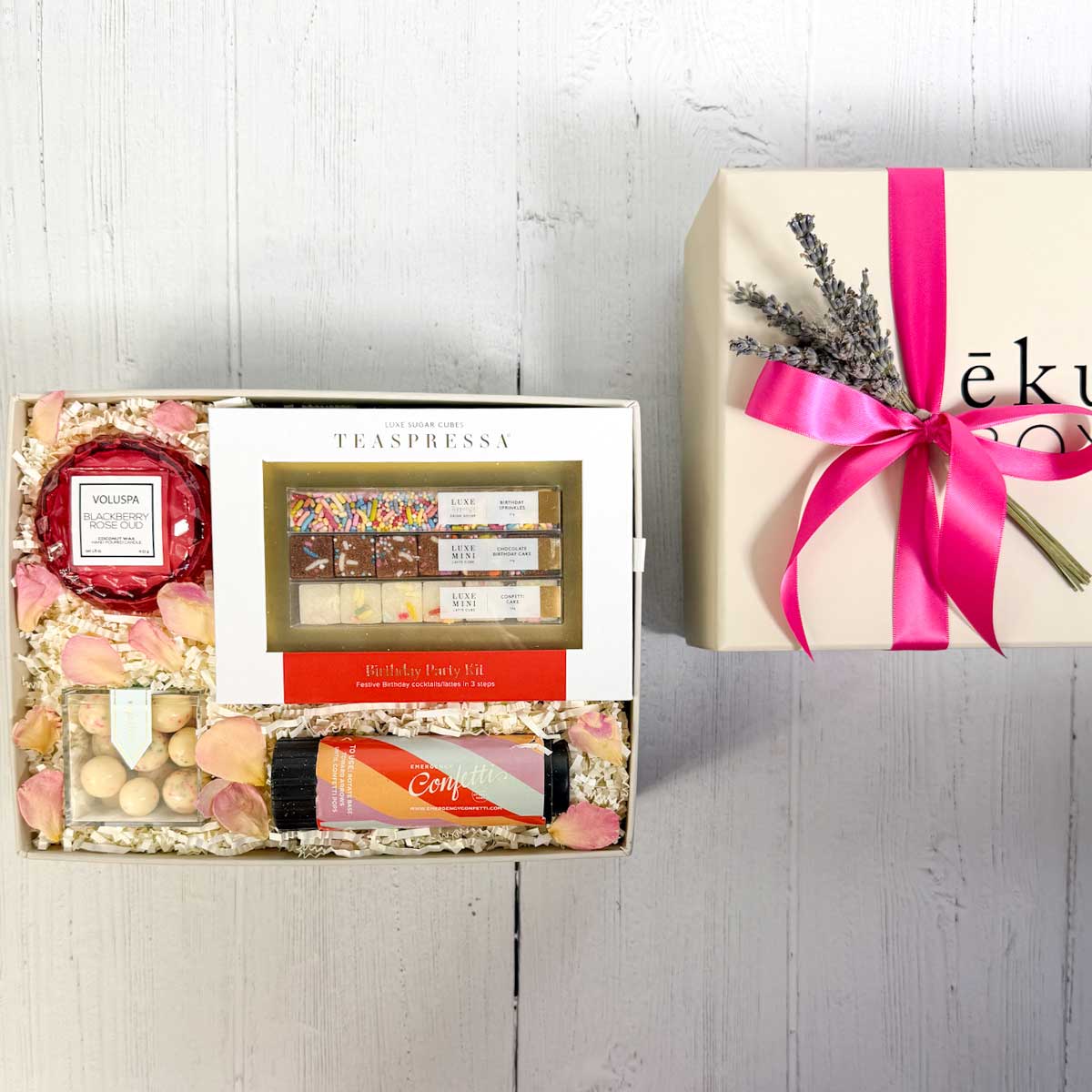 Birthday celebration Gift box with Voluspa candle and a Teaspressa birthday party kit, sugarfina candy and confetti on a marble surface.