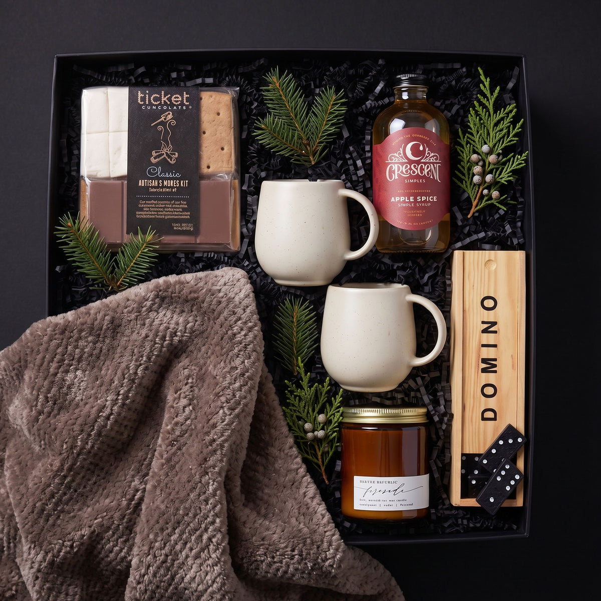 gift box filled with s'mores kit, 2 mugs, Crescent Apple Spice simple syrup, wooden box of dominoes, fireside candle and a brown throw
