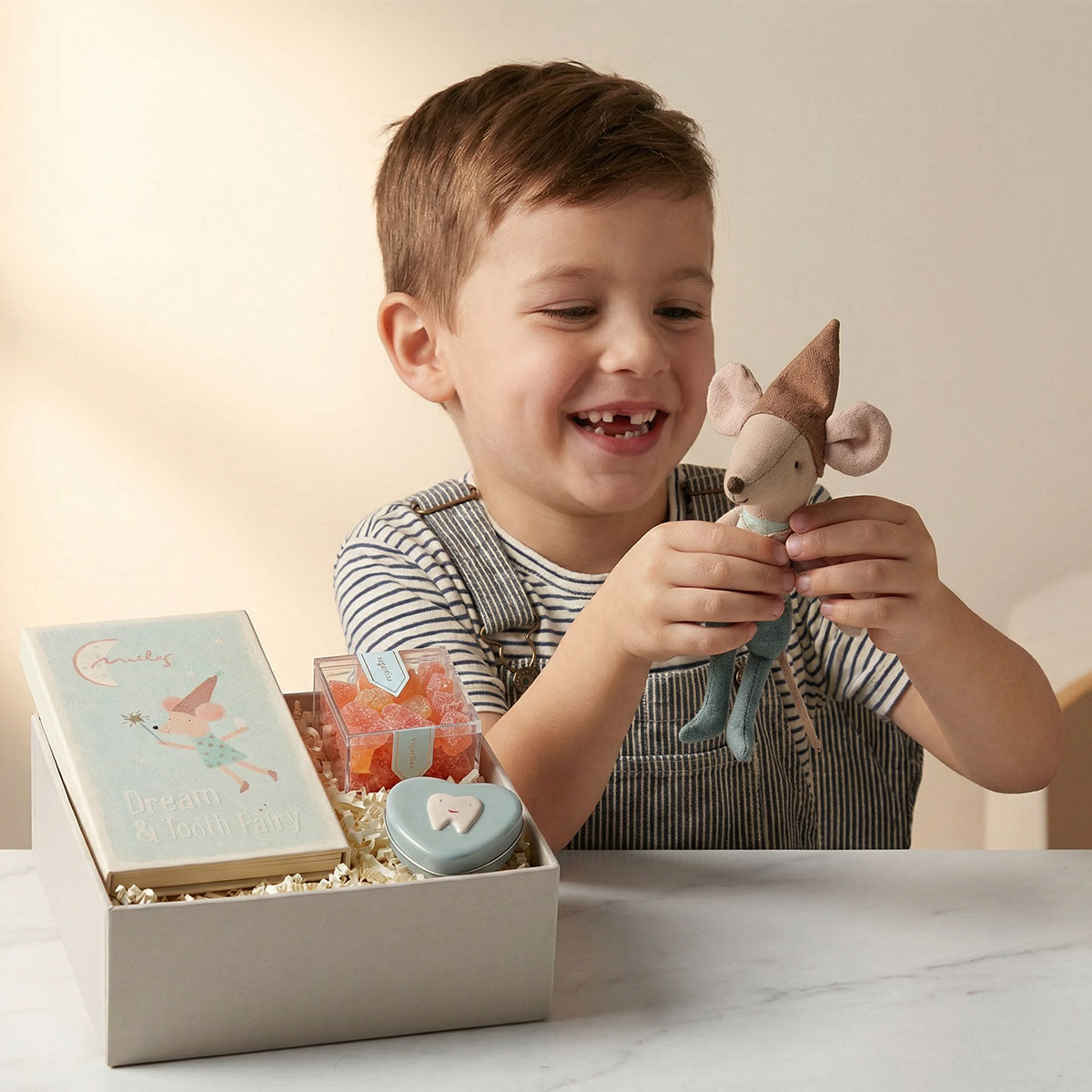 Child holding big brother tooth fairy with a gift box containing a keepsake box and sugarfina candy.