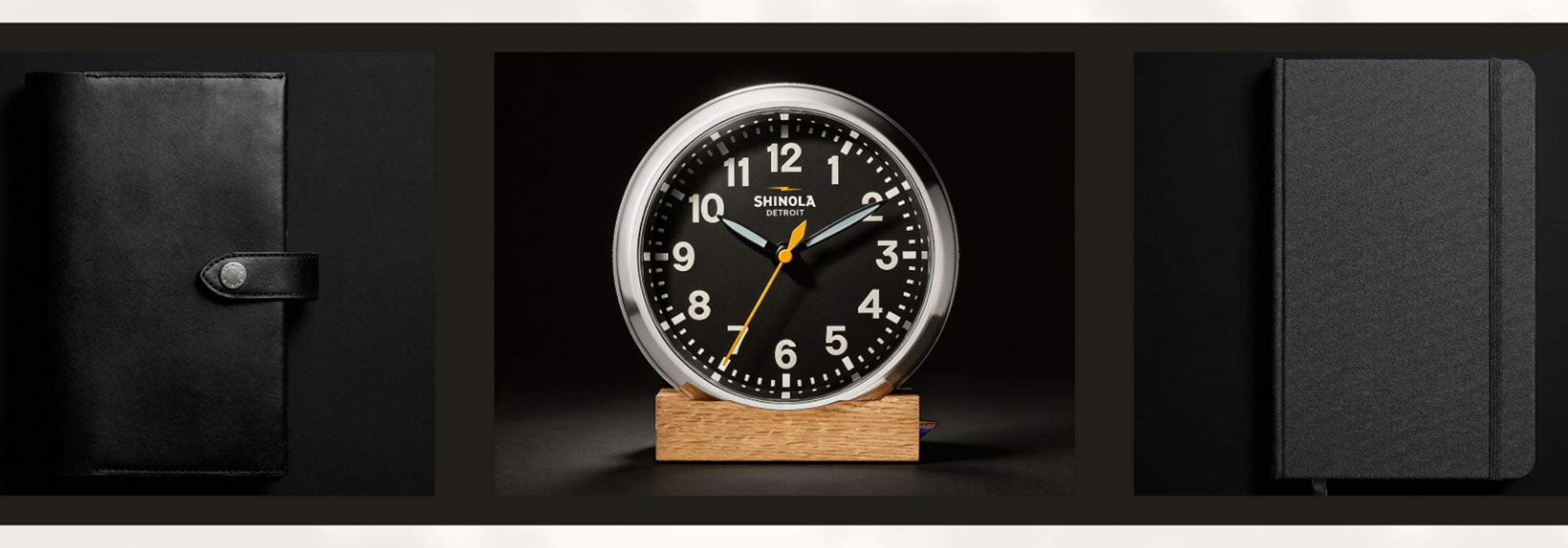 Shinola clock on a wooden stand with black leather cover and notebook in the background in the Shinola Collection