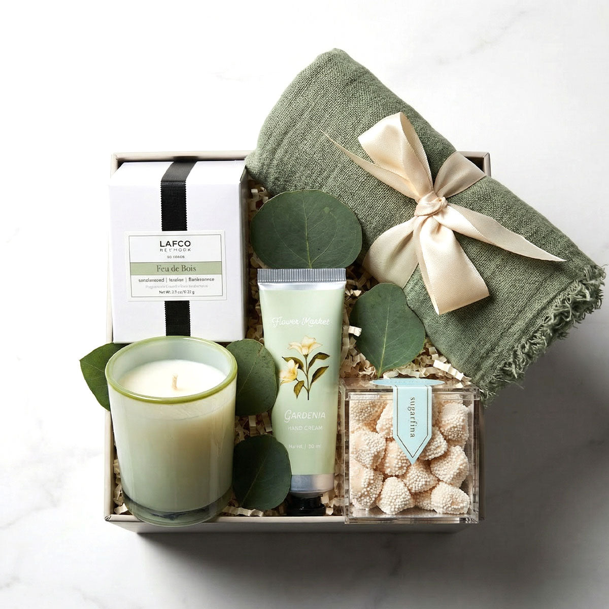 Luxury gift box with boho scarf, Lafco votive candle, gardenia hand cream, and champagne candy arranged in an elegant ekuBOX.
