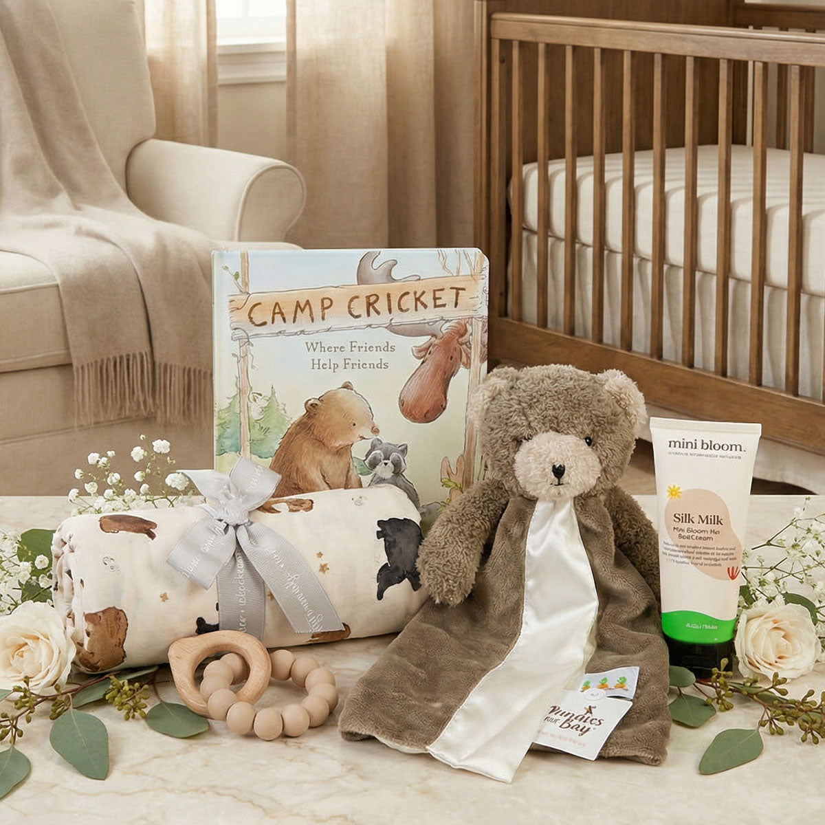 Baby gift set with bear, book, and other items on a table in a nursery.