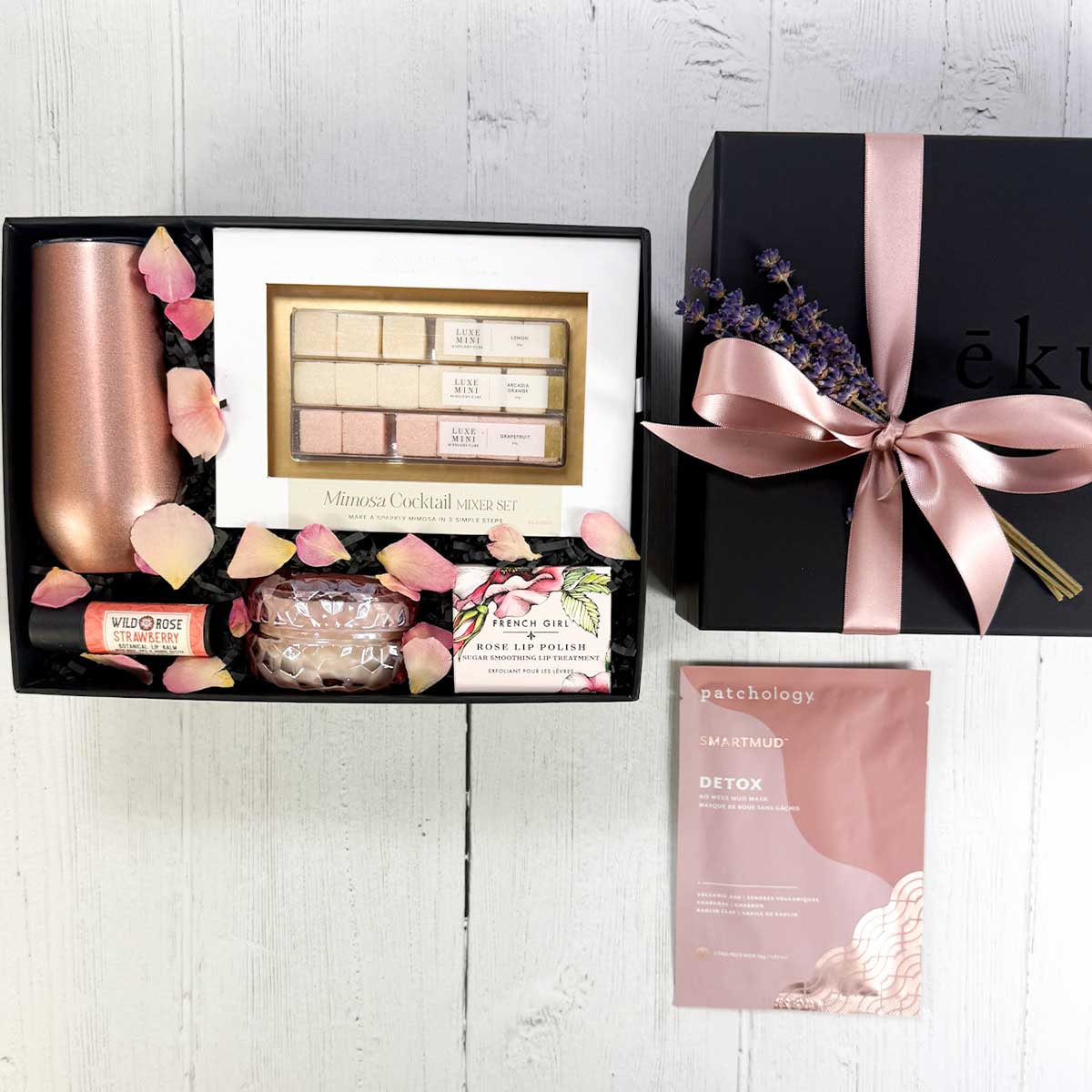 Bubble and Bliss spa gift box with Skincare and beauty products in a box, along with a mimosa kit and a stemless thermal champagne flute in a laydown shot with rose petals