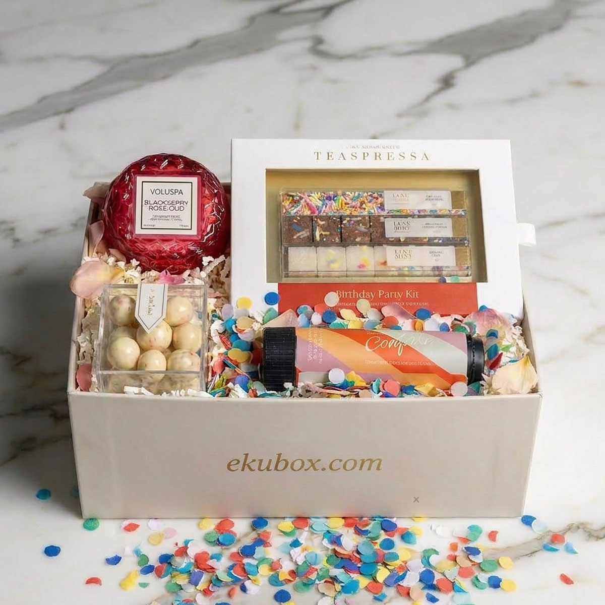 Birthday celebration Gift box with Voluspa candle and a Teaspressa birthday party kit on a marble surface.