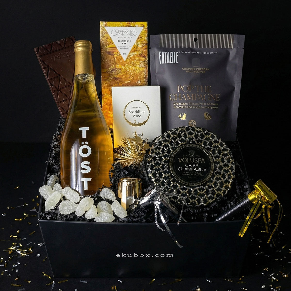 Cheers celebration gift box with TÖST sparkling non-alcoholic white tea, champagne candle, popcorn, wine gummies, and gourmet chocolate.