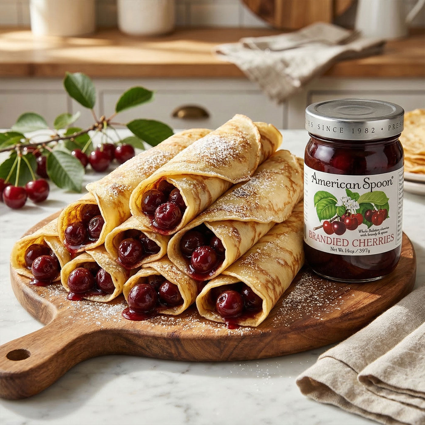 Crepes fiiled with with brandied cherries on a wooden board next to a jar of American Spoon brandied cherries.