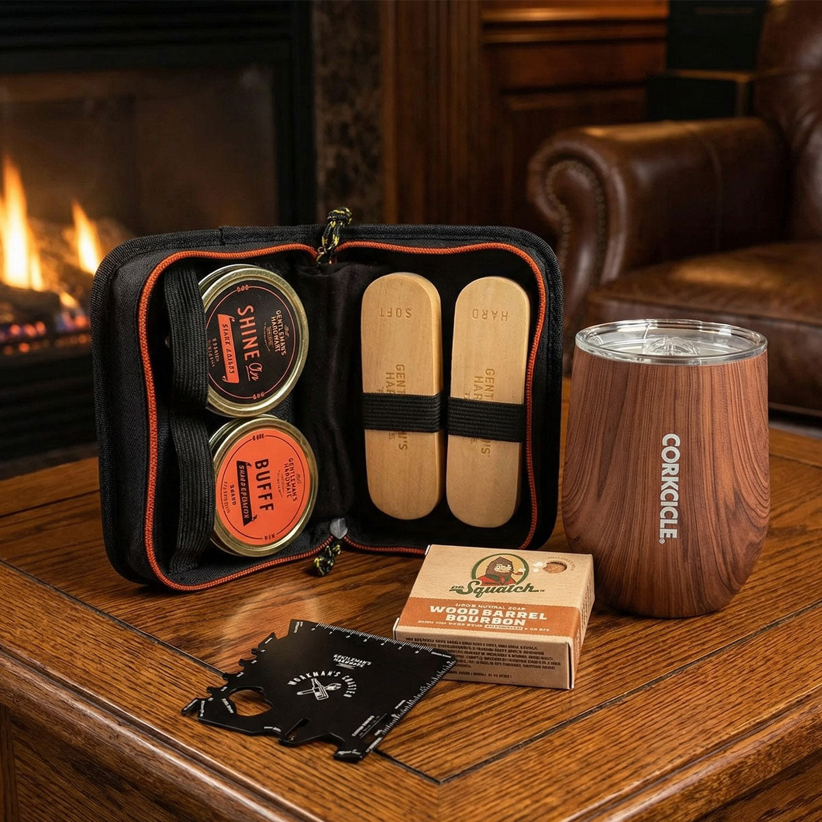 men' shoe shine kit, corkcicle cup, bar soap and multi-tool on wooden table