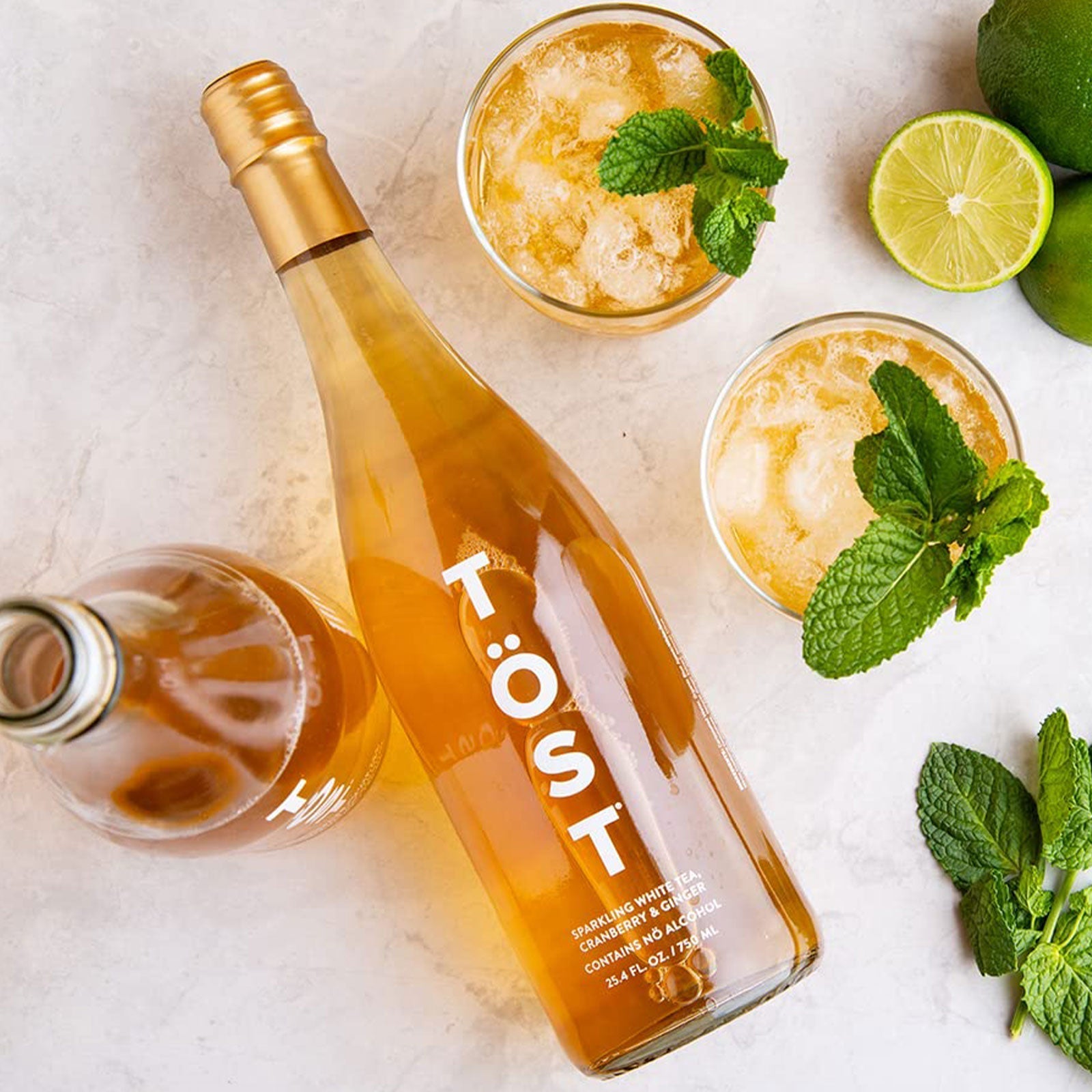 tost bottle of sparkling beverage with glasses of beverage with mint and lime