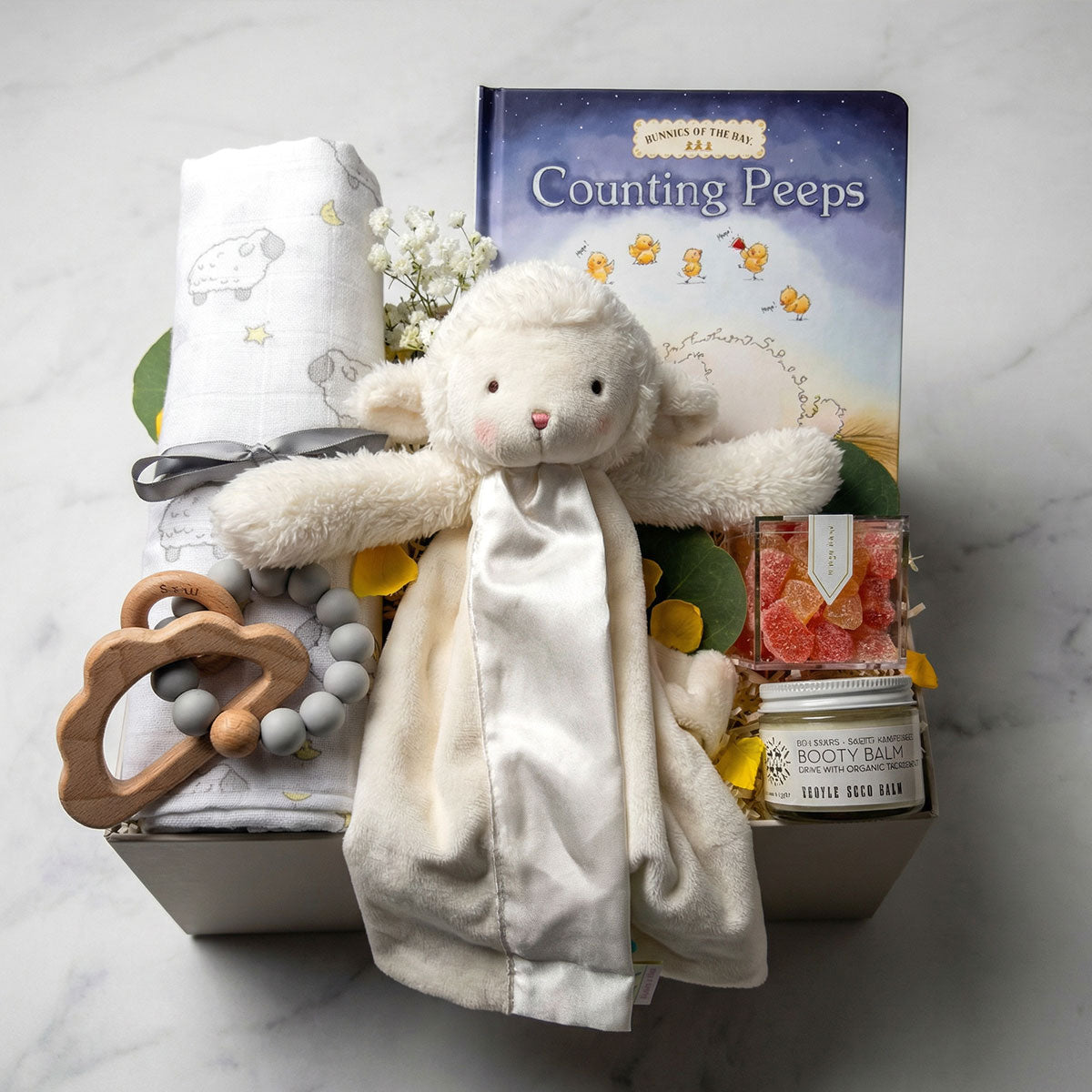 Modern gender-neutral baby gift box with a plush toy, essentials, and Sugarfina champagne bubble gummies.