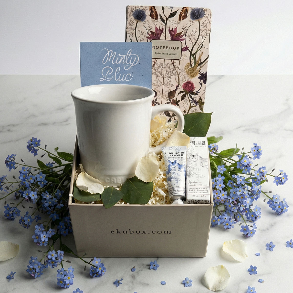 Sympathy gift box with Le Creuset mug, journal, and tea on marble. Comfort bereavement care package for condolences.