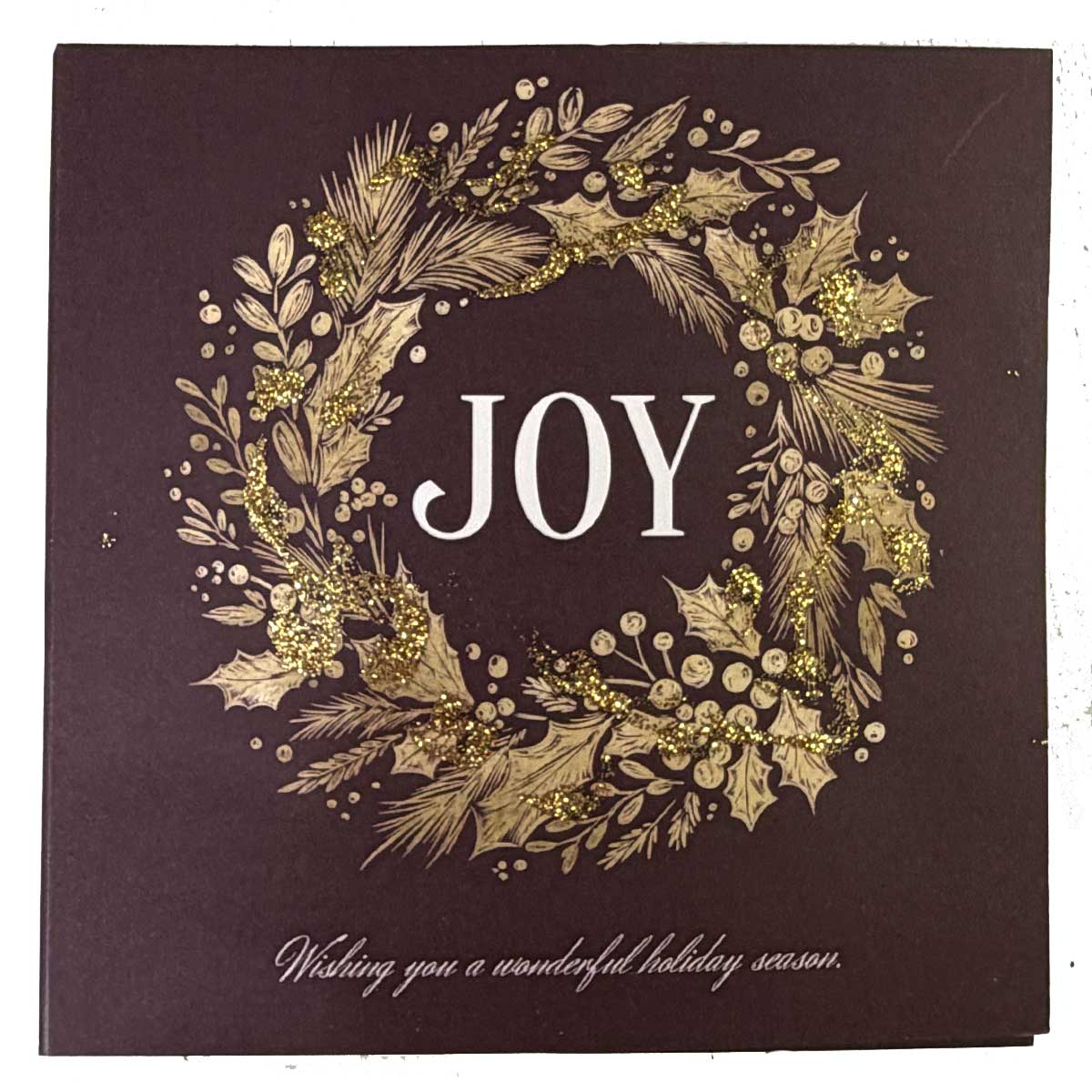 Decorative card with 'JOY' surrounded by foliage on a dark background