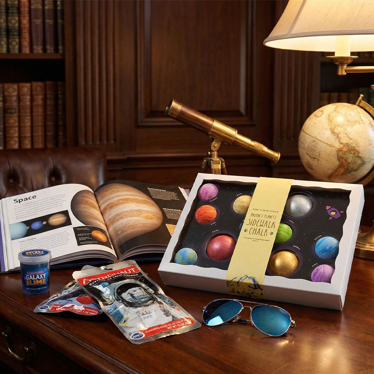 Tabletop scene with space-themed items including a book, box of chalk planets and sunglasses.