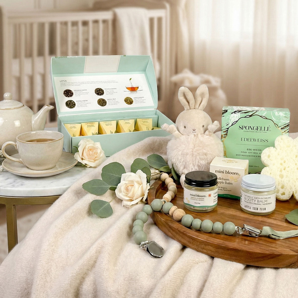 newborn gift box with teether, spongelle, tea and plush bunny in a baby room
