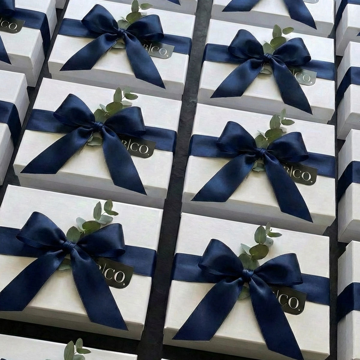 semi-custom white gift boxes for corporate gifting with navy ribbon and branded hang tags