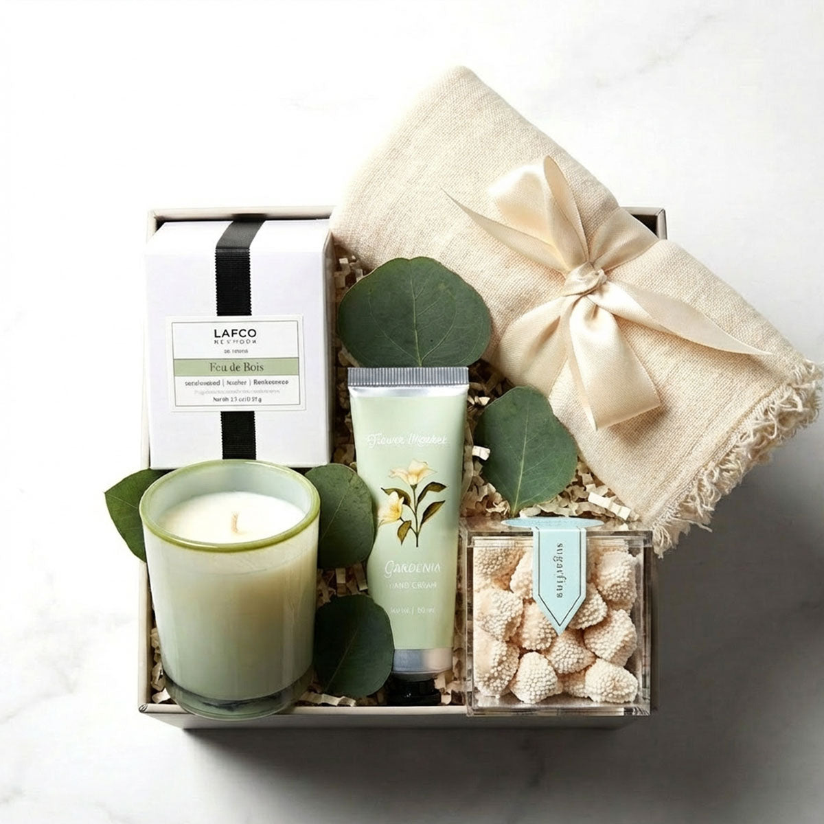 Gift set with Lafco candle, hand cream, and cookies, scarf in a box on a white background