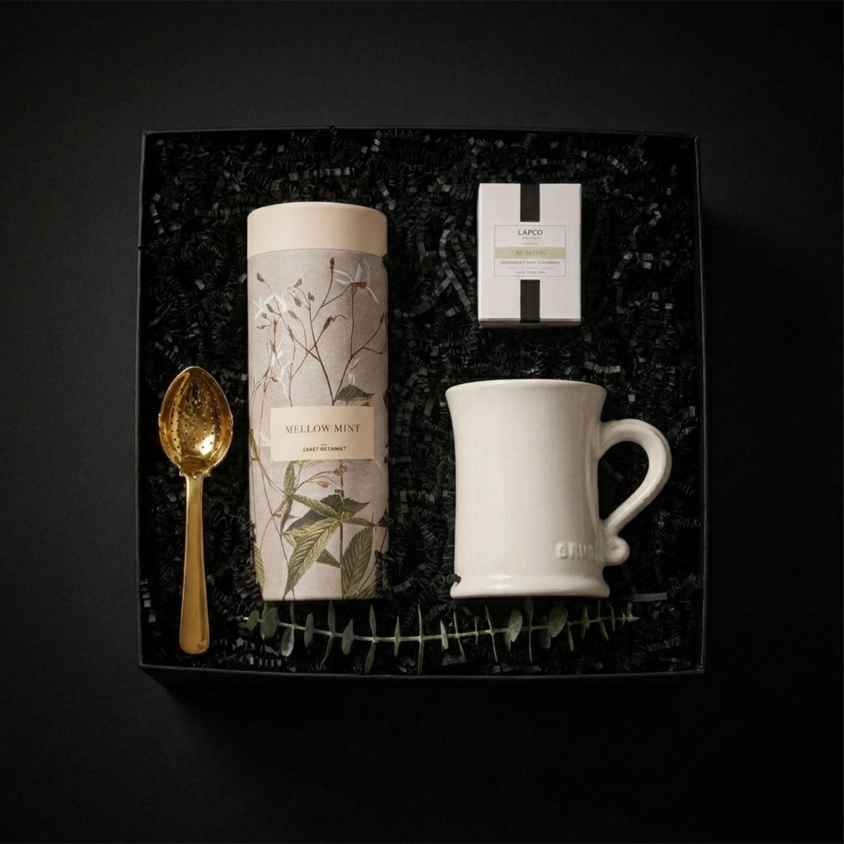 Tea gift set with Match Pewter mug, tea canister, and tea strainer with a Lafco candle in a box on a black background in a black box.