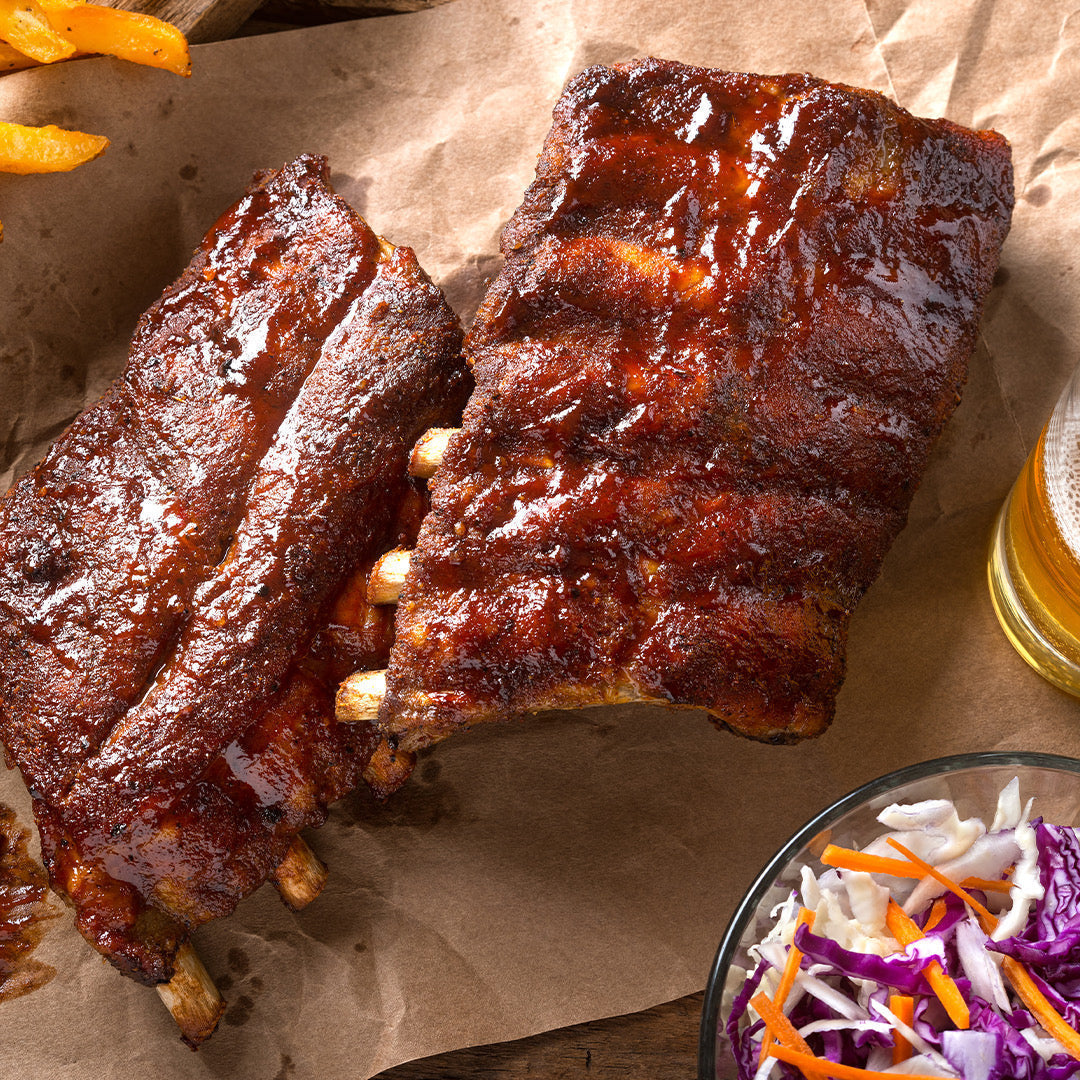 Slow-cooked BBQ ribs glazed with smoky sauce on a grill — low and slow recipe from ekuBOX Grill Masters Gift Box