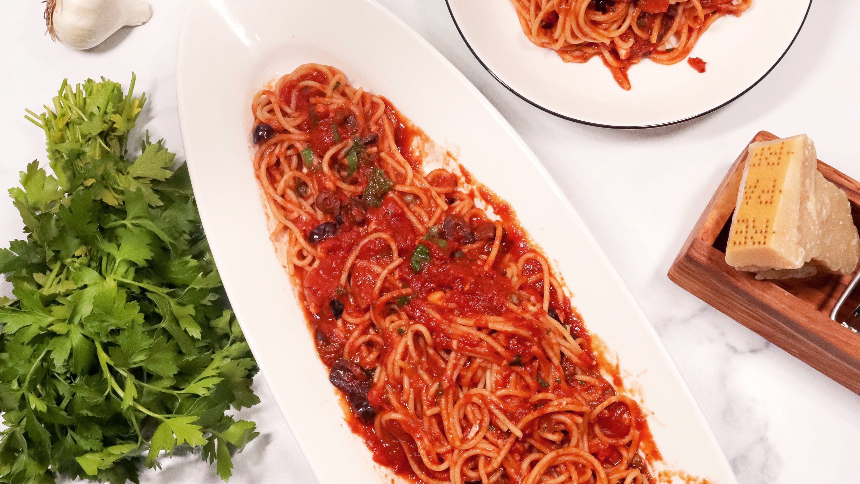 A bowl of classic Pasta Puttanesca with rich tomato sauce, olives, and capers — recipe from ekuBOX Sunday Sauce Gourmet Gift Box
