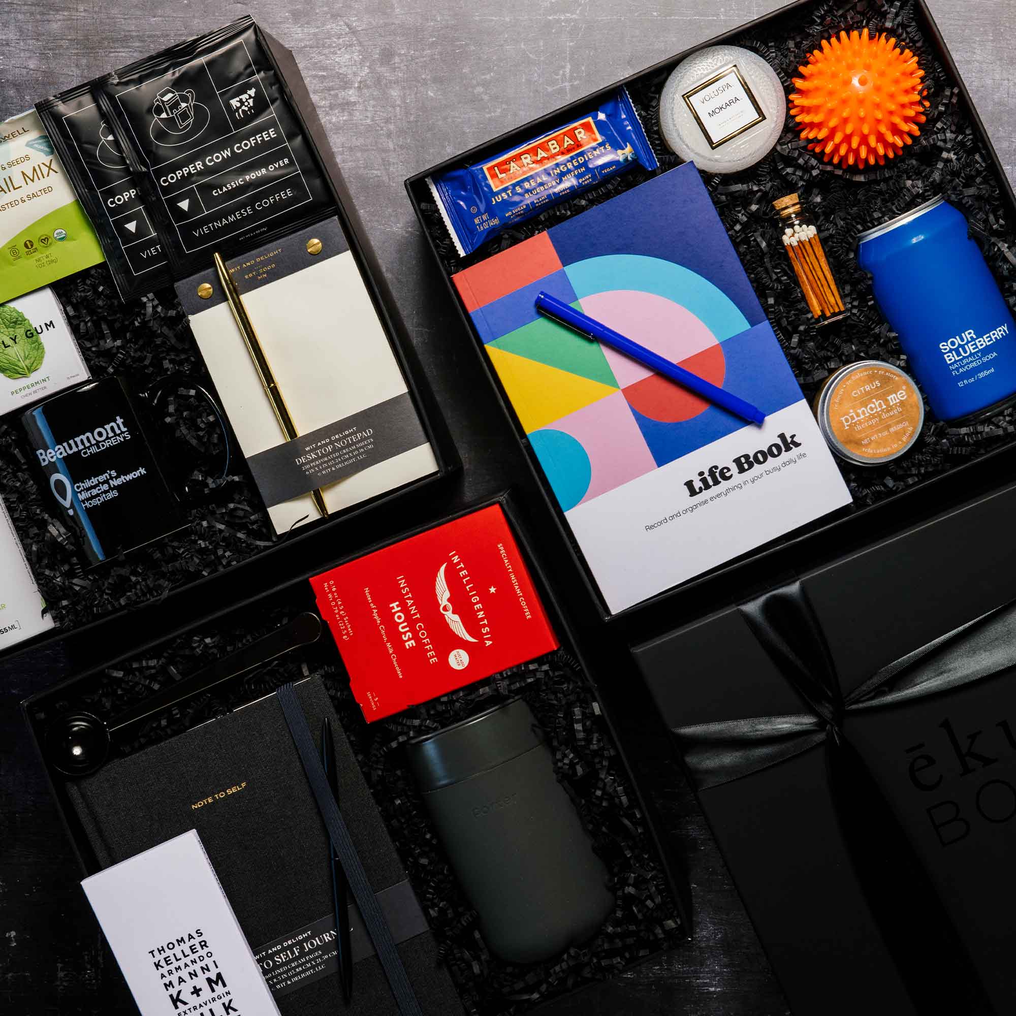 Black ekuBOX gift boxes filled with refined office and home office essentials, curated for employee appreciation gifting.