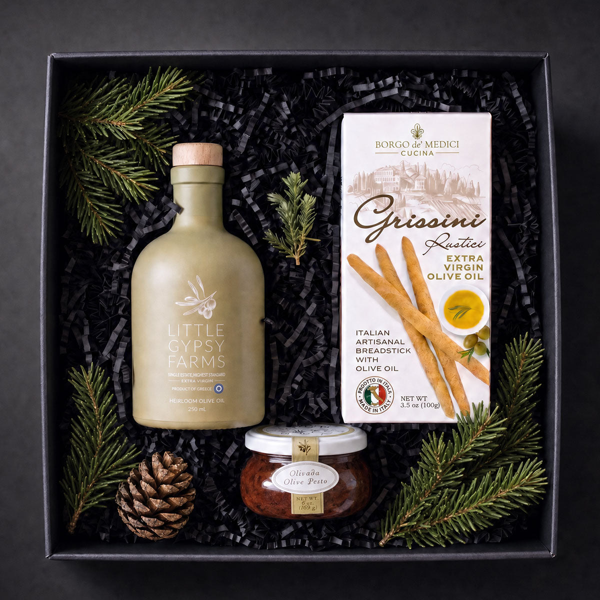 First Press Olive Oil GIFT Box with Olive oil by little gypsy farms, bella cucina olive pesto and grissini breadstics in a black gift box with holiday greens