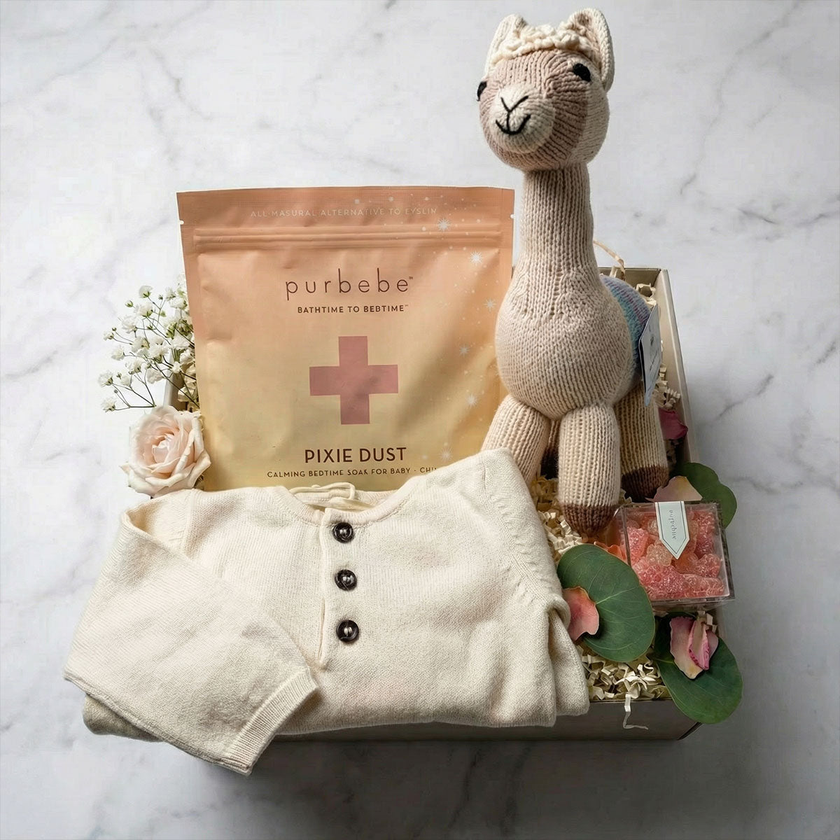 A baby gift box containing a hand-knit cotton llama, a organic cotton kangaroo pocket onesie