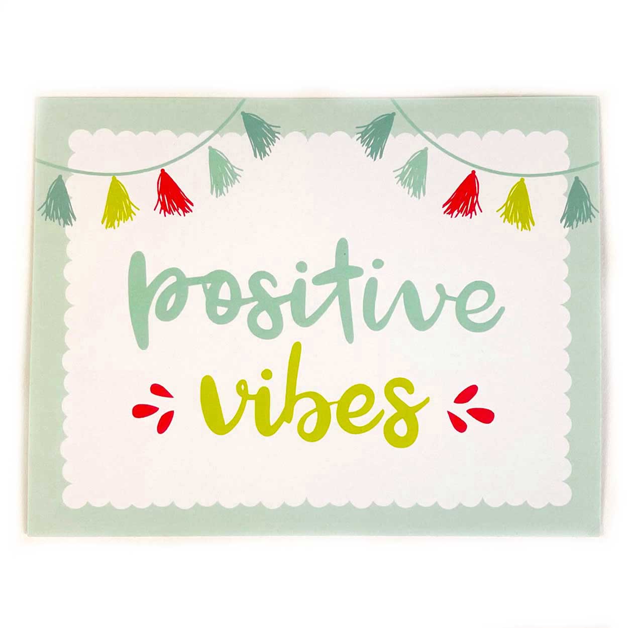 positive vibes in green on white background gift card choice with tassels on top