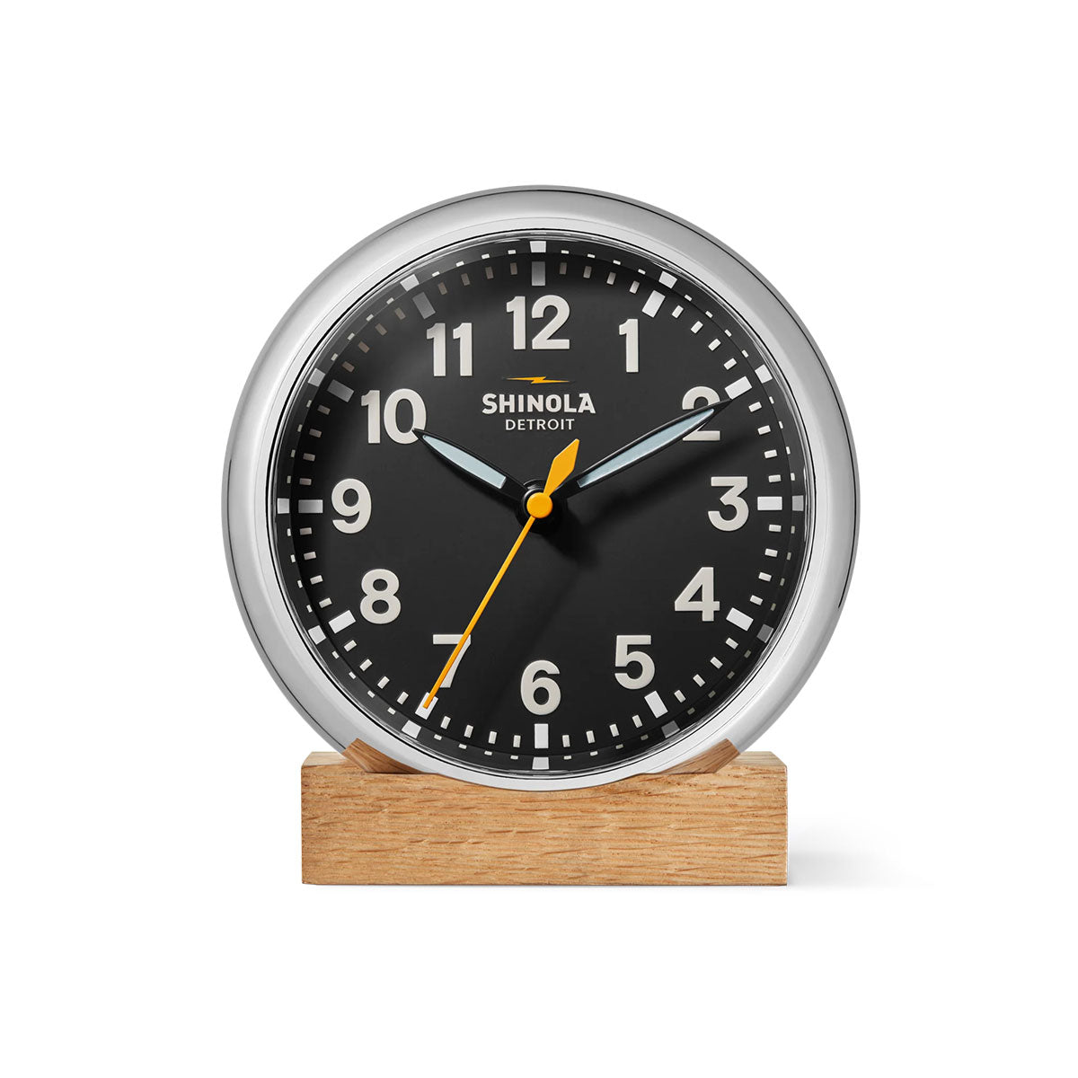Shinola Runwell clock with black face and silver rim on a wooden base