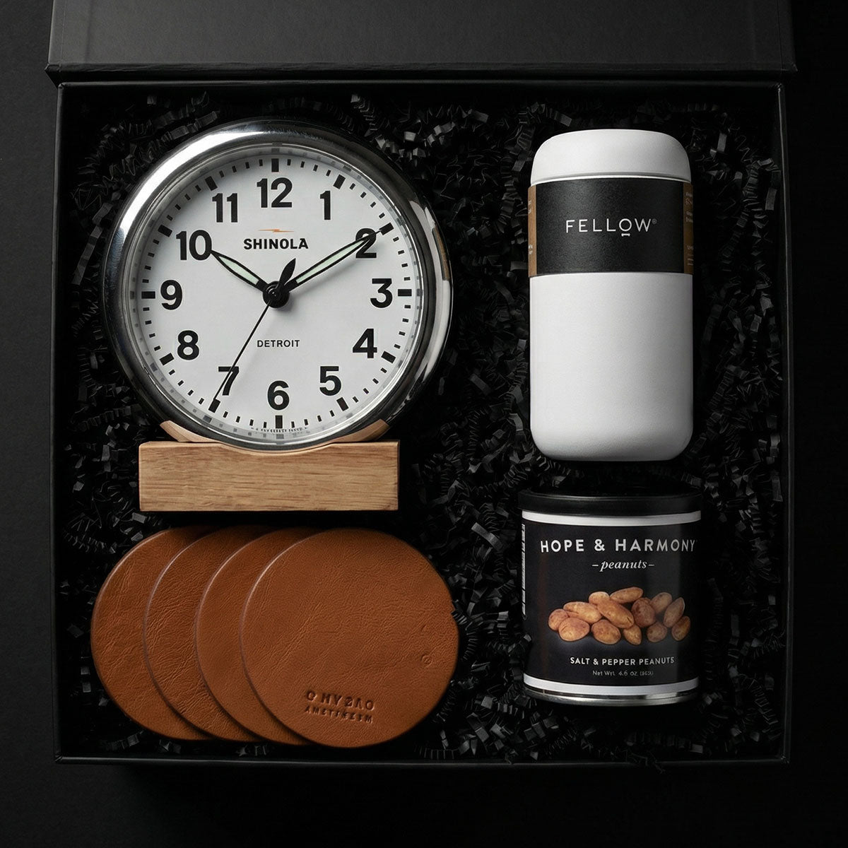 Gift set with Shinola clock, Fellow coffee container, leather coaster set, and Hope & Harmony peanuts in a box.
