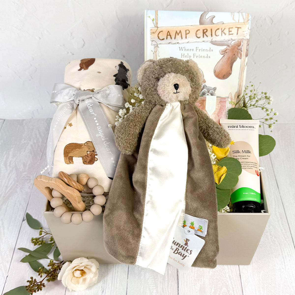 Baby Bear newborn gift box featuring a brown bear lovey, bear-print swaddle, silicone teether, baby cream, storybook, and Sugarfina gummies in a gift box.