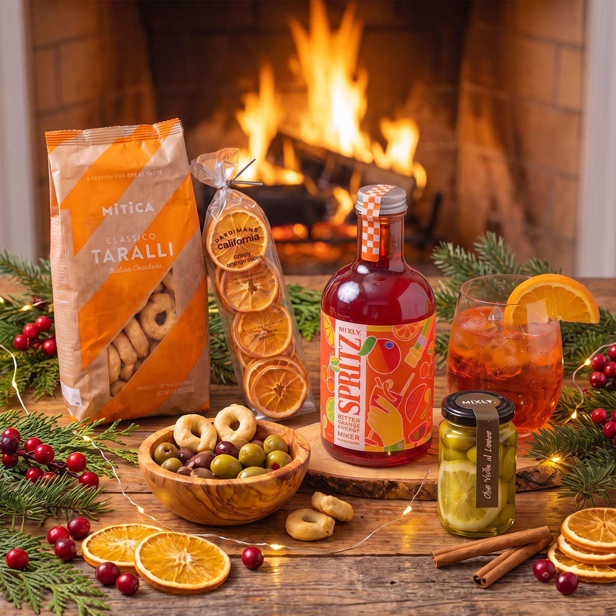  non-alcoholic Italian Spritz mix, olive wood dip bowl, dried oranges, jar of olives and lemon and taralli bag on a wood table in front of a fireplace