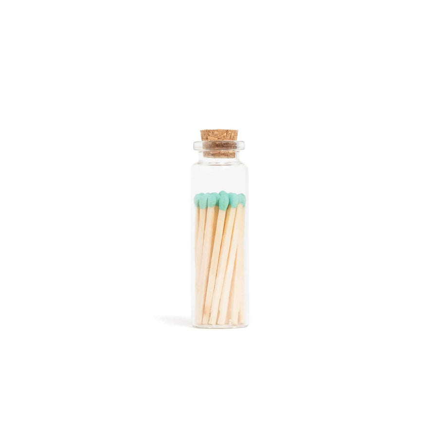 Glass bottle with cork lid containing matches on a white background