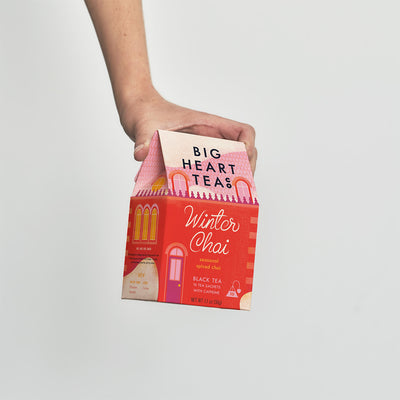 Hand holding a box of Big Heart Teas Winter Chai tea against a plain background