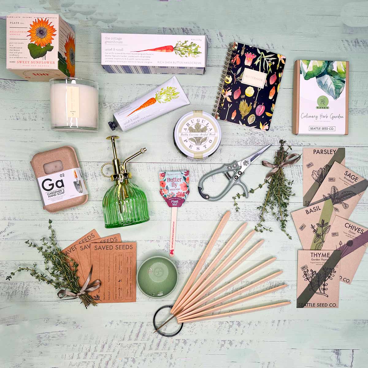 lay down of seeds, herbs, soap, mister, pesto, notebook, plant the box candle, stakes, pinch bowl