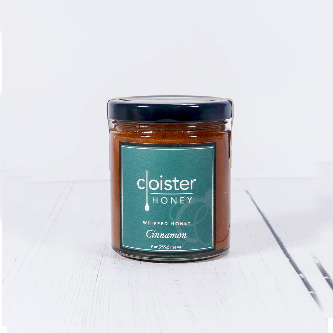 Cloister cinnamon honey in a glass jar with black top on a white background
