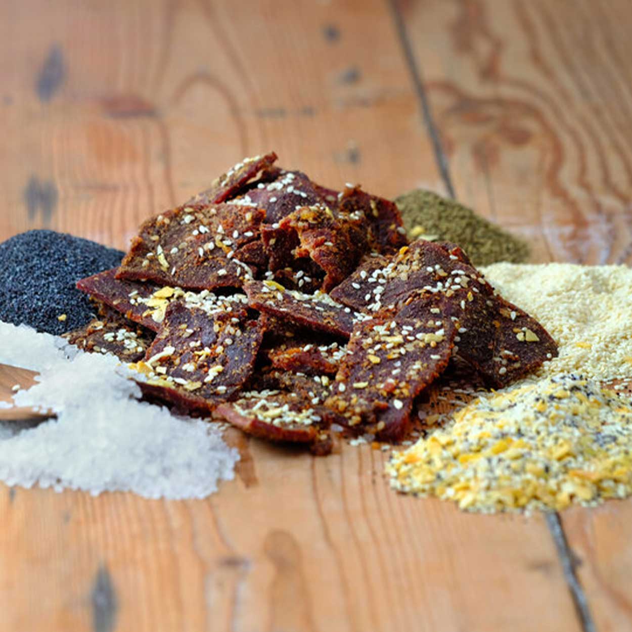 beef jerky on a wood table with spices and salt on the table