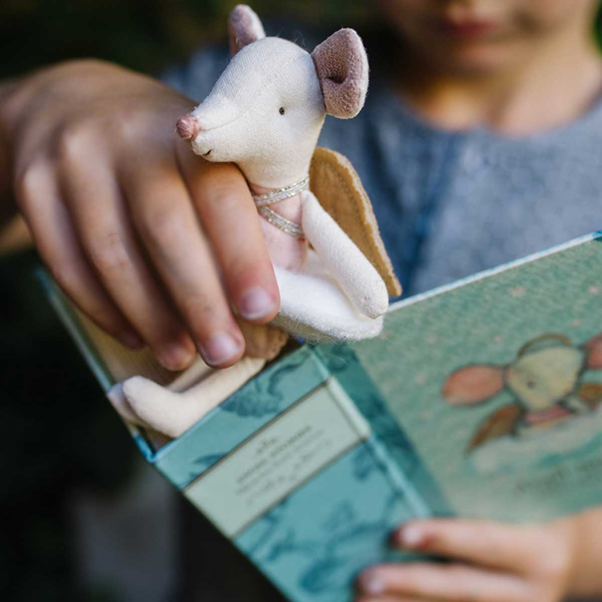 girls hand holding maileg angel mouse and book set 