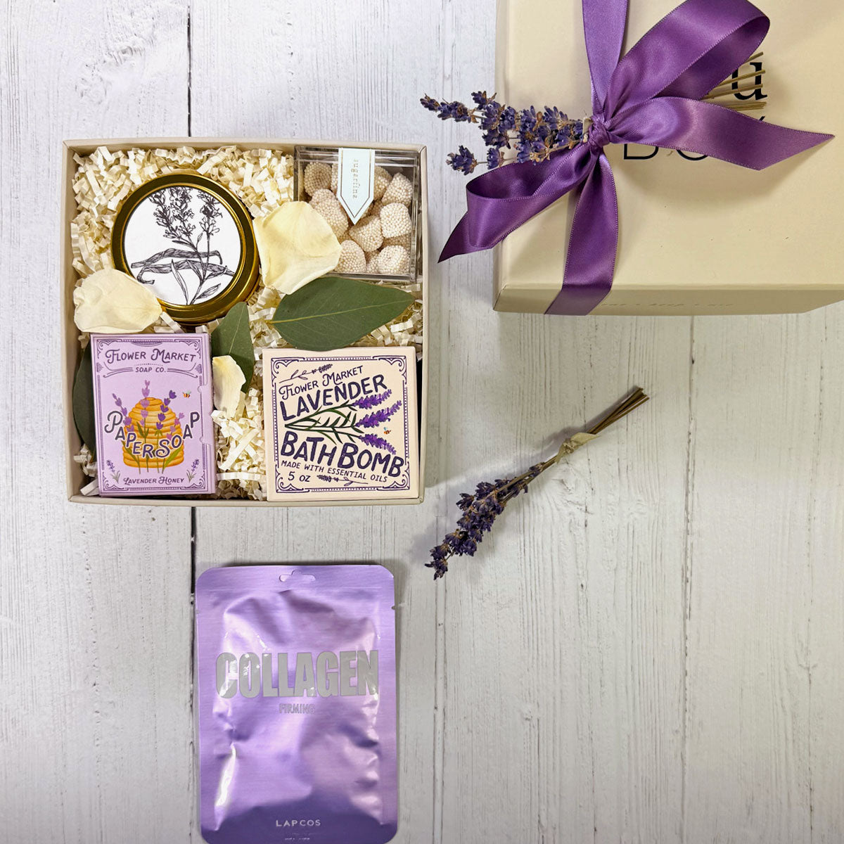Lavender Spa Gift Box featuring lavender candle, bath bomb, facial mask, paper soap, and gummies inside a small gift box.