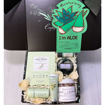 Gifting box with skincare products including aloe vera mask sheet and foot care items on a white background.