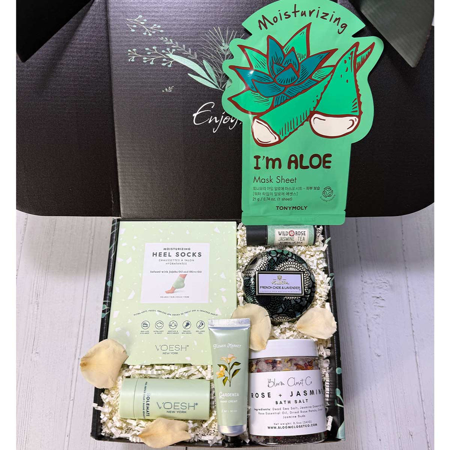 Gifting box with skincare products including aloe vera mask sheet and foot care items on a white background.