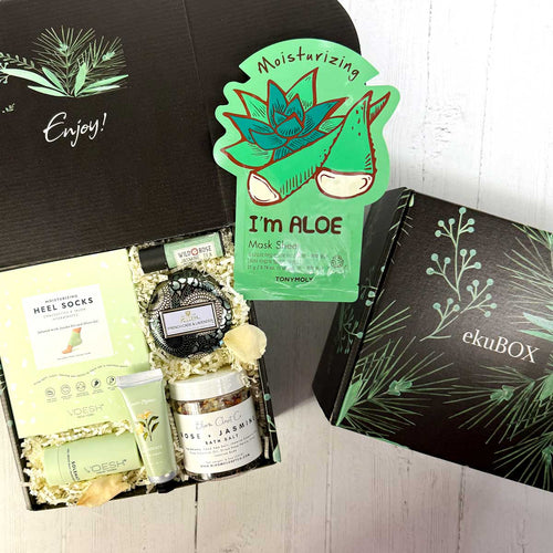 Gifting box with skincare products and 'I'm Aloe' mask sheet, featuring ekuBOX branding and self care products and a candle on a white background.