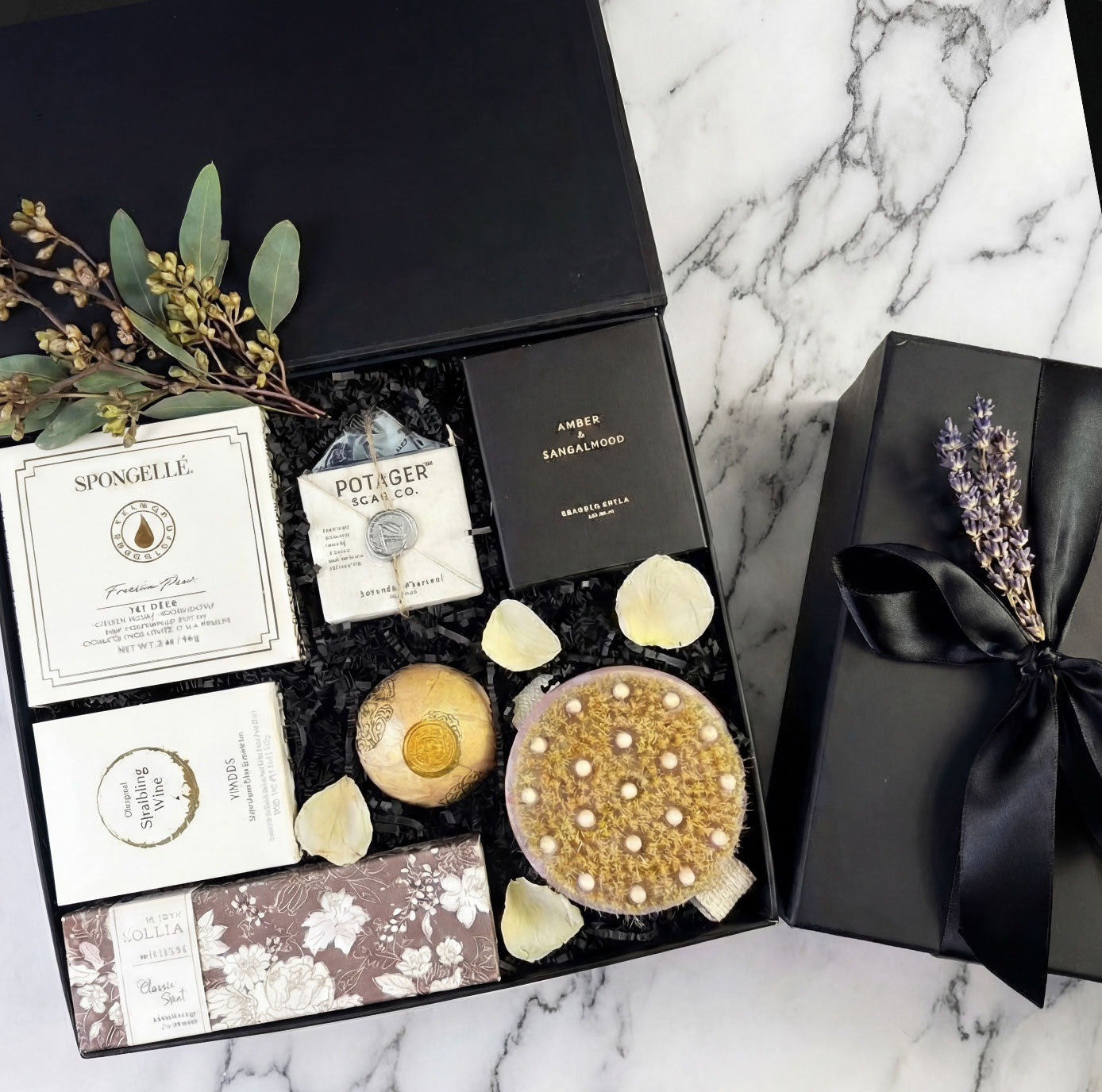 pampered luxury spa gift box with candle and bath soaps in a box with box top on marble background.