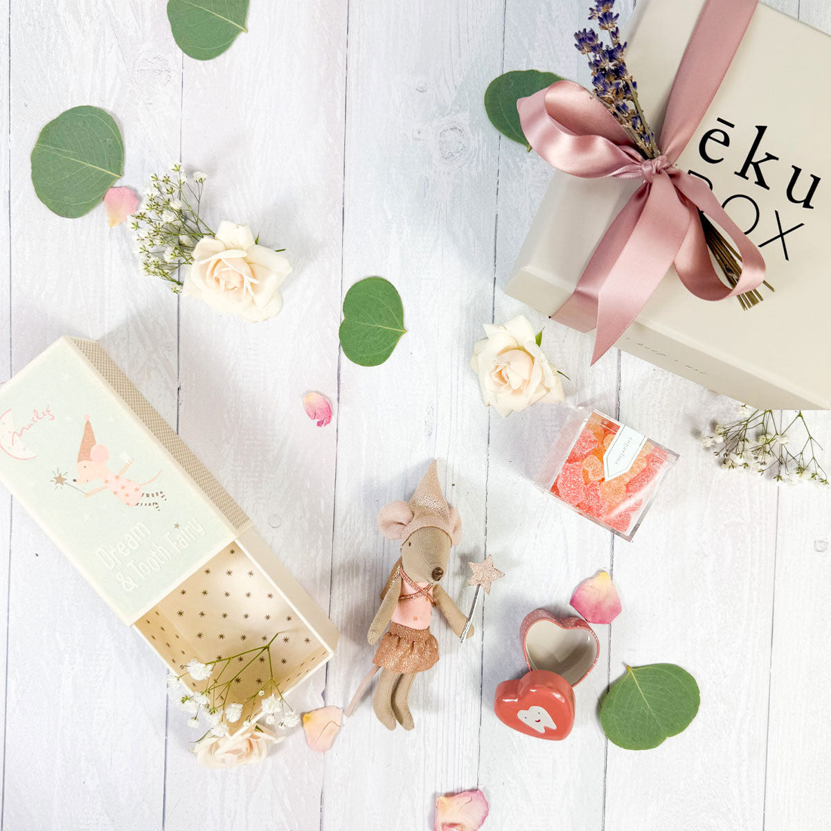 A laydown  Maileg Tooth Fairy mouse dressed in a gold tutu and hat, with a sparkly backpack, alongside a heart-shaped tooth holder and gift box.