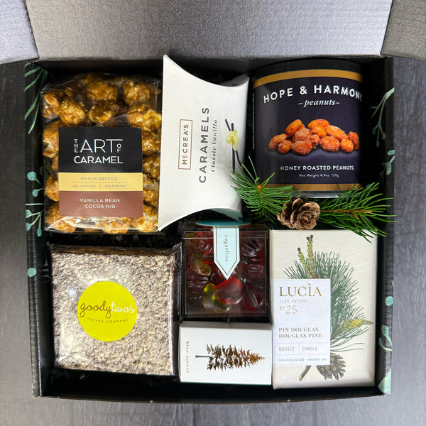 Assorted gourmet snacks in an ekuBOX mailer box with popcorn, caramels, toffe,e and Sugarfina gummies.